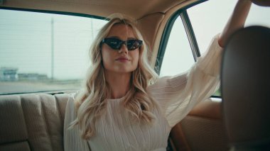 Kadın yolcu arka koltukta rahat bir klasik araba kapanışı yapıyor. Zarif güneş gözlüklü güzel kız açık pencereli seyahat ediyor yaz rüzgarının tadını çıkarıyor. Güzel bayan turist özgürce eğleniyor
