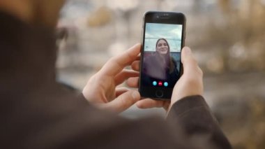 Erkek eller çevrimiçi kız arkadaşını arıyor. Gülümseyen kadın web uygulamasında cep telefonu ekranını sallıyor. Bilinmeyen erkek arkadaş sokakta akıllı telefonlu uzak bir kızla konuşuyor. Video konferansı kullanan mutlu çift