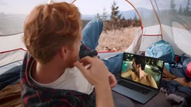 İki adam bilgisayarla video konferansı hakkında konuşuyor. Gezgin adam dağ gezisinde web kamerasının önünde çadır kuruyor. Neşeli mutlu arkadaşlar tatilde haberleri paylaşırlar. Mutlu kardeşler çevrimiçi arıyor