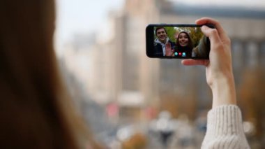 Sokaktan akıllı telefonları arayan bir kadın. Yakın plan. Mutlu çift sanal konferans uygulamasında ekran paylaşım haberleri sallıyor. Bilinmeyen kız tatilde ailesiyle internetten konuşuyor.