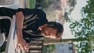 Rahatlamış melomanyak parkta dikey olarak akıllı telefon yazıyor. Eğlence alanında tek başına çalışan yakışıklı İspanyol bir turist cep telefonu kullanıyor. Yetişkin adam kafedeki kablosuz kulaklıklarda dinleniyor.