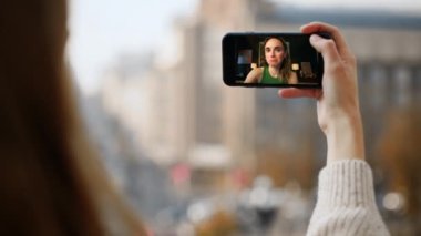 Kasaba kızı görüntülü konuşma yapıyor. Gülümseyen kız sohbeti akıllı telefon ekranı paylaşımı haberlerinde. Sokakta cep telefonu tutan kimliği belirsiz bir kadın. Sanal konferansta iletişim kuran uzak kız arkadaşlar