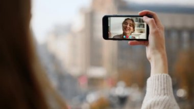 Akıllı telefon ekranında gülümseyen kız el sallıyor. Sokakta iletişim uygulaması kullanarak kamerayla sohbet eden arkadaşlar. Elinde cep telefonu olan tanınmamış bir kadın. Sanal çağrıdaki uzak kız kardeşler