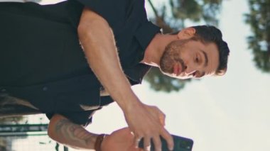Mutlu adam, şehir gözlem güvertesinde cep telefonuyla konuşurken video kaydediyormuş. Gülümseyen İspanyol blogcu görüntülü konuşma. Rahat, şık bir turist cep telefonu kamerasıyla konuşuyor.