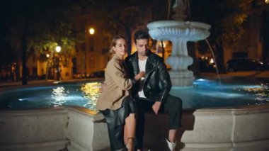 Güzel bir kadın, aydınlatılmış şehir çeşmesinde adama nazikçe sarılıyor. Havalı, birbirine aşık bir çift akşamın tadını çıkarıyorlar. Yakışıklı, kendine güvenen, çekici kız arkadaşını kucaklayan adam.