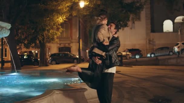 一个浪漫的男人带着女孩在大街上 快乐微笑的夫妻享受彼此凝视的约会 漂亮可爱的家伙在晚上旋转美丽的女朋友 入迷的人在傍晚公园里聚在一起 — 图库视频影像