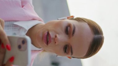 Kulaklıklı bayan akıllı telefon ekranında dikey sipariş videosu çekiyor. Sokakta cep telefonu uygulaması kullanarak kendine güvenen zarif bir serbest portre. Kulaklık takmış bir kadın telefondaki e-postaları kontrol ediyor.