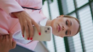 İş kadını telefon haritasını kullanarak şehir merkezinde dikey görüntülere bakıyor. Zarif bir kadın cep telefonu uygulamasına bakıyor. Elinde belge klasörü tutan çekici bayan akıllı telefonu kaydırıyor..