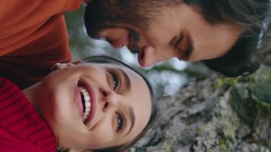 Romantik yakışıklı adam, geniş orman ağacına yaslanmış mutlu kadına sarılmış dikey olarak yaklaş. Sevgi dolu genç bir çift gülerek sonbahar doğasında hafta sonunun tadını çıkarır. Neşeli, yumuşak aile çifti rahatlıyor, neşe duyuyor.