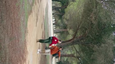 Orman yolunda yürüyen iki mutlu yürüyüşçü güzel doğayı dikey olarak seyrediyor. Sırt çantalarıyla parkta gezen sevimli bir çift. Aktif neşeli aile, el ele tutuşup öpüşüyorlar..