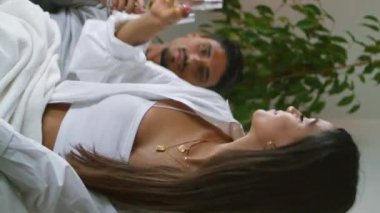 Evli insanlar rahat bir yerde dikey olarak şarap içiyorlar. Otelde tatilini kutlayan romantik bir çift. Pozitif aile alkolden zevk alıyor. Kocasına içecek bardakları getiren güzel bir kadın. 