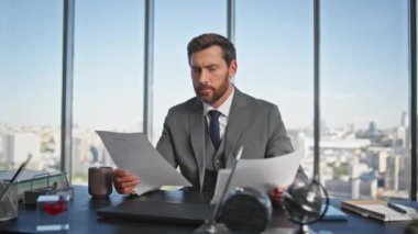 Ofis masasında başarılı bir CEO 'ydu. Düşünceli yönetici şehir manzarasında kontrat belgelerini tutuyor. İş yerindeki pazarlama raporlarını kontrol eden olgun iş adamı sakallı.