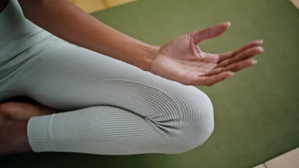 Yoga model zen fingers lying feet indoors close up. Unknown sporty girl sitting lotus pose on rubber mat. Athlete lady hands meditating at carpet making spiritual practices. Calmness harmony concept