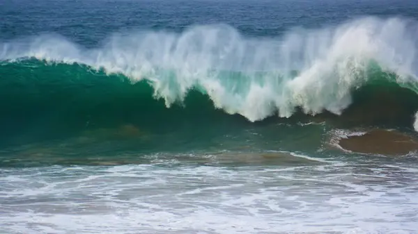 Huge ocean surf barrelling in super slow motion. Powerful wave rolling breaking surface on gloomy day. Dangerous sea water crashing swelling in stormy morning. Extreme turquoise coastal seascape.
