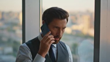 Panoramik pencerede profesyonel akıllı telefon çözme problemi. Yönetici, iş görüşmesi için ortakla görüşüyor. Orta yaşlı işadamı ofiste anlaşmayı tartışıyor.