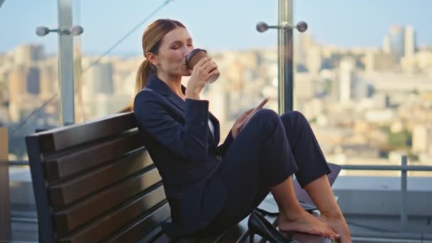 朝のテラスを休むコーヒーを飲んでいる冷たい労働者 平和な女性マネージャーは オフィスバルコニーで休憩を楽しんでいる携帯電話をチェックします スマートフォンを持っている飲料を飲む美しい笑顔のビジネスマン — ストック動画