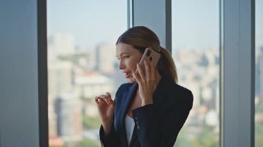 Şirket yöneticisi cam ofiste hücreden konuşuyor. Panoramik pencerede cep telefonuyla iletişim kuran güzel bir kadın gülüyor. Mutlu genç iş kadını akıllı telefondan dostça sohbet ediyor.