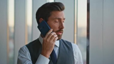 Portre kendinden emin lider panoramik ofis vitrininde cep telefonuyla konuşuyor. Yakışıklı bir danışman iş problemleri hakkında pazarlık yapıyor. Başarılı orta yaşlı bankacı iş adamı konuşuyor. 