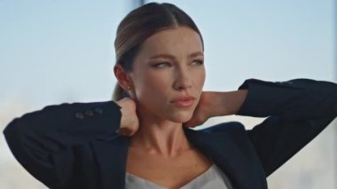 İş yerinde boyuna masaj yapan çok çalışan bir kadın. Ofis çalışanı gözlerini kapatıyor panoramik pencereye tapınak sürterek acı çekiyor. Yorgun iş kadını işten sonra dinleniyor..