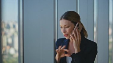Şirket çalışanı cep telefonuyla sohbet ediyor. İyi haberleri paylaşan mutlu kadın panoramik pencerenin ortağına iş projesini anlatıyor. Gülümseyen ofis hanımı emlakçı arkadaşça sohbet ediyor.
