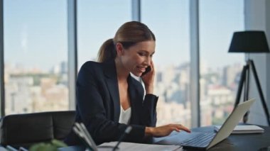 Panoramik ofiste gülümseyen bir yönetici cep telefonuyla konuşuyor. Rahatlamış şirket yöneticisi bilgisayarla akıllı telefon sohbetinin tadını çıkarıyor. Kaygısız kadın çalışan. Nöbetçi partnerle daktilo konuşması.