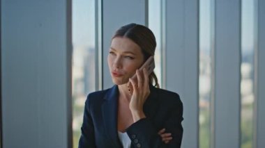 Emlakçı panoramik pencereden cep telefonunu arıyor. Yakın plan genç iş kadını CEO, ofisteki hücre danışmanlığı müşterisi ile konuşuyor. Kendine güvenen profesyonel kadın pencerenin önünde anlaşma projesini tartışıyor..