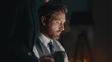 Karanlık Ofis 'te şirket danışman asistanı yakın plan. Satış ekibi proje için birlikte çalışıyor. Profesyonel bir kadın kahve getirip, yorgun ve bıkkın bir adamla konuşur..