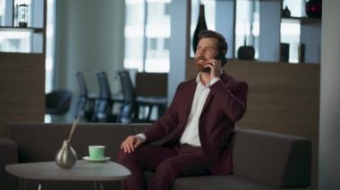 İş adamı modern rahat ofis penceresinden arama yapıyor. Neşeli sakallı girişimci yönetici koridorda mali iş planı cep telefonunu tartışıyor. Başarılı CEO, profesyonel şirket kavramı.