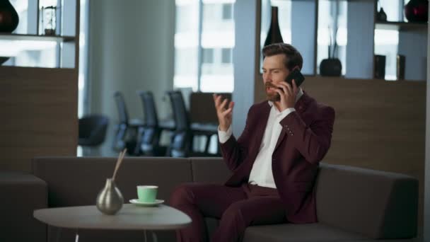 怒っているビジネスマンは現代の企業のオフィスの内部で電話ソファーを投げます プロのコールキャビネットを作る経営幹部真面目な起業家 不幸なビジネスオーナーが金融プランの携帯電話を話す — ストック動画