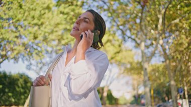 Güneş Işıkları Sokağı 'nda telefonla konuşan kendine güvenen bir kadın var. Ciddi, olgun bir kadın akıllı telefonu elinde tutan iş anlaşmasını tartışıyor. Profesyonel iş kadını yaz caddesinde cep telefonuyla konuşuyor.