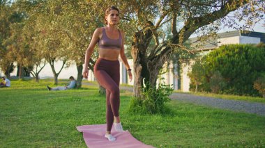 Yoga mankeni Sunny Park 'ta asana egzersizi yapıyor. Olgun bir kadın yaz doğasında bacakları bükerek vücut egzersizi yapıyor. Sportif bayan tek ayak poz egzersizi yapıyor. Farkındalık yaşam tarzı dengesi 