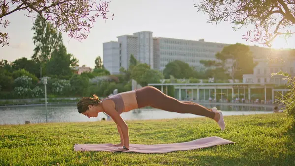 Active athlete plank position at sunbeams nature. Slim sportswoman practicing yoga training at sunrise. Flexible woman enjoying soft sunlight stretching cobra pose at summer morning. Sport concept