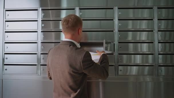 オフィスビルのポストをチェックする成功した男 廊下の金属製のメールボックスロッカーから 手紙を受け取るハンサムな男 現代ホールのスーツのビジネスマン — ストック動画