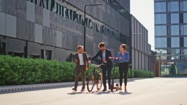 Mutlu ekip şehir merkezinde birlikte yürüyor. Gülümseyen kurumsal insanlar elektrikli scooter ile işe gidip geliyorlar. Takım elbiseli ofis müdürleri güneşli bölgeye gidiyorlar. Neşeli iş ortakları.