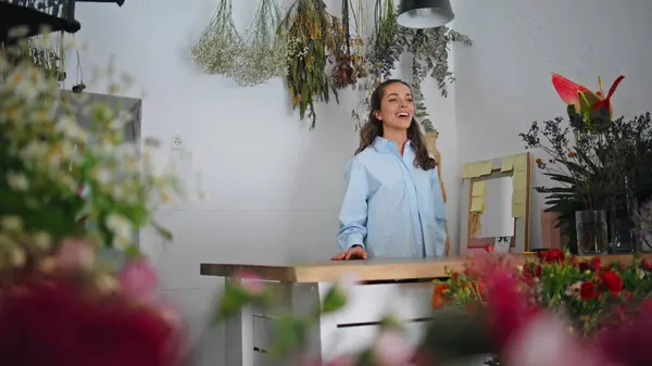 Positive flower shop decorator talk in shop. Beautiful woman florist owner smiling in floral background. Laughing seller entrepreneur speak positive energy in plant store. Modern businesswoman concept