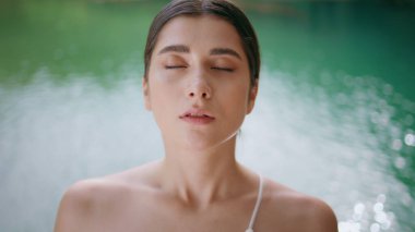 Turkuaz göl doğasında yoga egzersizi yaparken derin nefes alan rahat bir kadın. Nazik kız suratı, meditasyon yapan kamera görüntüsü. Odaklanmış sporcu kadın yaz gününde sakinlik uyumu hissediyor