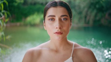 Mavi gözlü model tropikal plaj portresi çiziyor. Turkuaz göl havuzu doğası yaz gününde kameraya bakan ciddi bir genç kız. Yogini yoğunlaştırılmış, dışarıda dinleniyor. Cennet ormanları manzarası