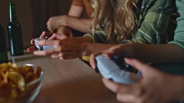朋友们手牵着操纵杆在家里玩电子游戏 无法辨认的年轻人按下沙发上竞争的按钮 使用游戏垫坐在沙发客厅的未知游戏玩家 — 图库视频影像