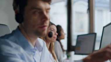 Müşteri hizmetleri birlikte çalışıyor. Ofisteki profesyonel destek ekibi müşterilere yardım ediyor. Kulaklıkla konuşan arkadaş canlısı bir kadın. Güvenilir adam teknik danışman iş yerinde ekranı işaret ediyor