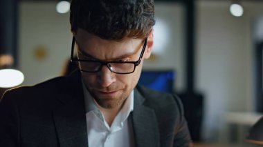 Yakın çekim yöneticisi lamba ışığında ofiste çalışıyor. Ciddi bir borsacı karanlık iş yerinde planlama stratejisi düşünüyor. Düşünceli iş adamı, mali uzman aşırı çalışma, iş çözümü arıyor.