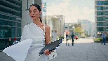 Kulaklıklı kız işe giderken bilgisayarında iş evrakları taşıyordu. Şık bir iş kadını, zarif bir görünümle şehir caddesinde yürüyen kablosuz kulaklıklarla konuşuyor. Kulaklıkla konuşan güzel bayan.