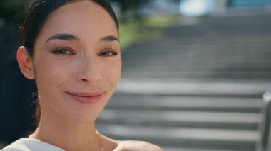 Sunny caddesinde modern akıllı telefonu elinde tutan şık bir model. Güzel esmer kadın dışarıda telefon özçekimi yapıyor. Gülümseyen bir kameraya benzeyen zarif bir kız. Bayan blogcu gülümsüyor.