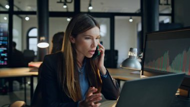 Sinirli yönetici lamba ışığında cep telefonuyla konuşuyor. Sinirli iş kadını, ofis vizitesinde başarısız finansal anlaşma satış sonuçlarını tartışmak için geç saatlere kadar çalışıyor. Stresli kadın kendini yorgun hisseder.