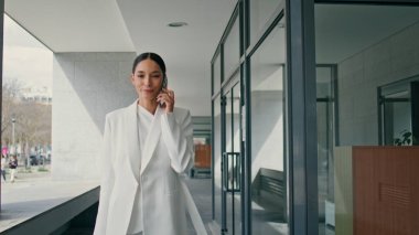 Genç bayan yönetmen modern iş merkezinin koridorunda yürüdüğünü söylüyor. Şık, mutlu bir iş kadını telefonda gülümsüyor. Muhteşem bayan patron, telefon görüşmelerini ofise giderken tatmin etti..