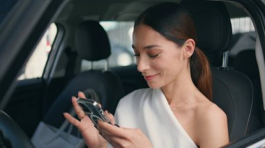 Akıllı telefondan sosyal medyayı izleyen zarif bir kız arabanın ön koltuğunda. Gülümseyen, rahatlamış bir kadın, mesajlaşırken telefonla mesajlaşırken gülümsüyor. Güzel esmer şoför, arabasında telefonla oturuyor.