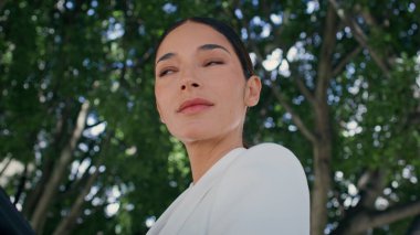 Zengin iş kadını Green Park 'ta dikilip yakından bakıyor. Zarif beyaz takım elbise giymiş, doğada poz veren muhteşem genç bir kadının portresi. Şık bir iş kadını iş molasında dışarıda dinleniyor.