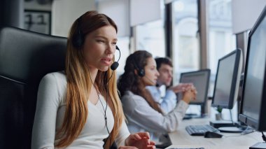 Kulaklıkla müşteri dinleyen yardımcı operatör. Satış müdürü yardım hattındaki sorulara cevap veriyor. Açıklama yapan genç bayan teknik asistan görev başında talimat veriyor. Profesyonel müşteri hizmetleri