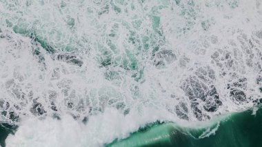 Köpüklü okyanus suyu çok yavaş sıçrıyor. Hava manzarası sersemletici fırtına dalgası kasvetli bir günde dalgalanan beyaz köpükle sert dalgalar yaratıyor. Güçlü deniz yıkama kıyıları. Deniz manzarası kavramı