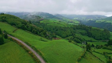 Yeşil tepeleri kaplayan gök gürültülü bulutlar hava manzarası. Panoramik çam ağacı dağları kasvetli hava. Huzurlu sisli gün ormanı yamaçları ve dağlık arazi. Sakin dramatik ortam