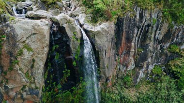Yüksek kayalıklardan akan su havadan görünüyor. Güçlü güç akışı yosunlu kayaları eziyor. Tepelerde hızla akan tehlikeli soğuk sıvı. Destansı ölçekli doğa gezisi ilham konsepti